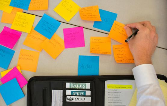 Close-up of a hand placing sticky notes in an organized layout.