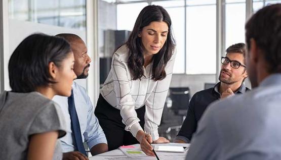Lead engineering manager standing at table with engineers discussing technical writing