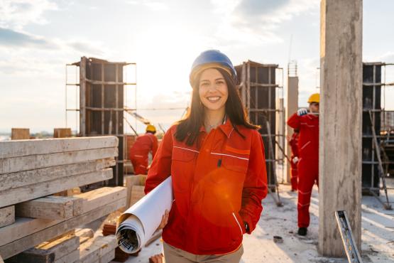 worker standing with a blueprint rolled up in their arm.