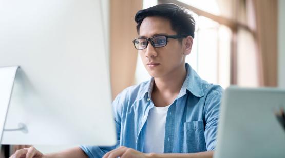 Man at desk in front of laptop studying for engineering analytics certificate.