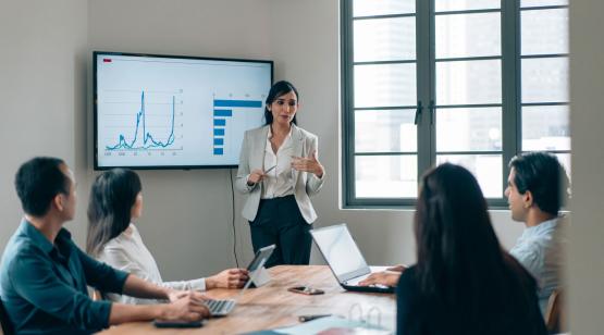 Woman standing in front of screen with graphs teaching students in the six sigma black belt certificate program