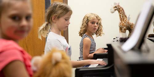 Students in a Piano Safari class with stuffed giraffe and lion