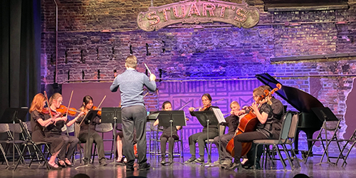 people on stage playing stringed instruments