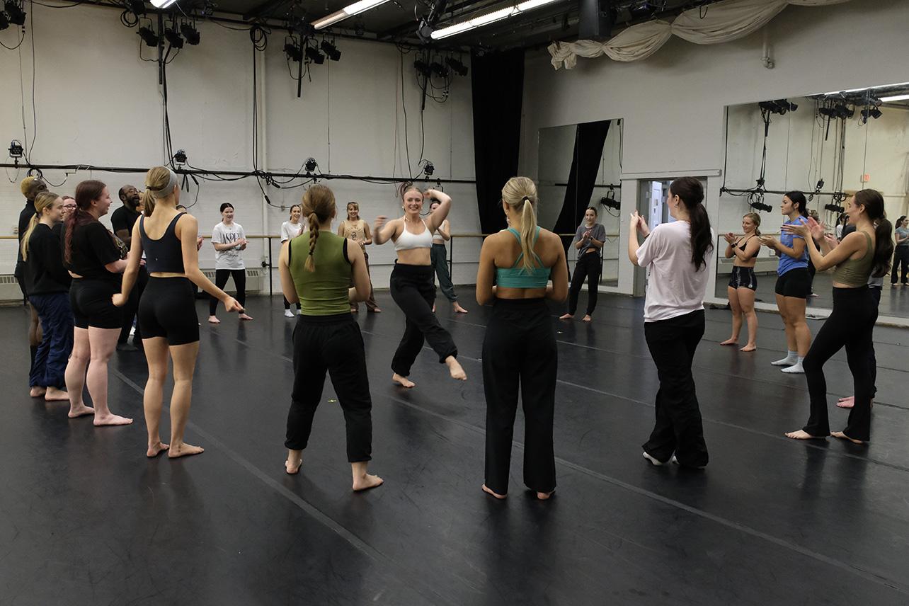 Dancers in a circle rehearsing in a studio