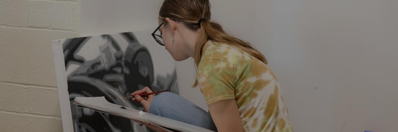 An Ohio University student working on a painting