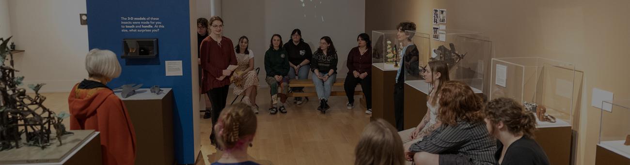 Students gather in a museum space to discuss the exhibits.