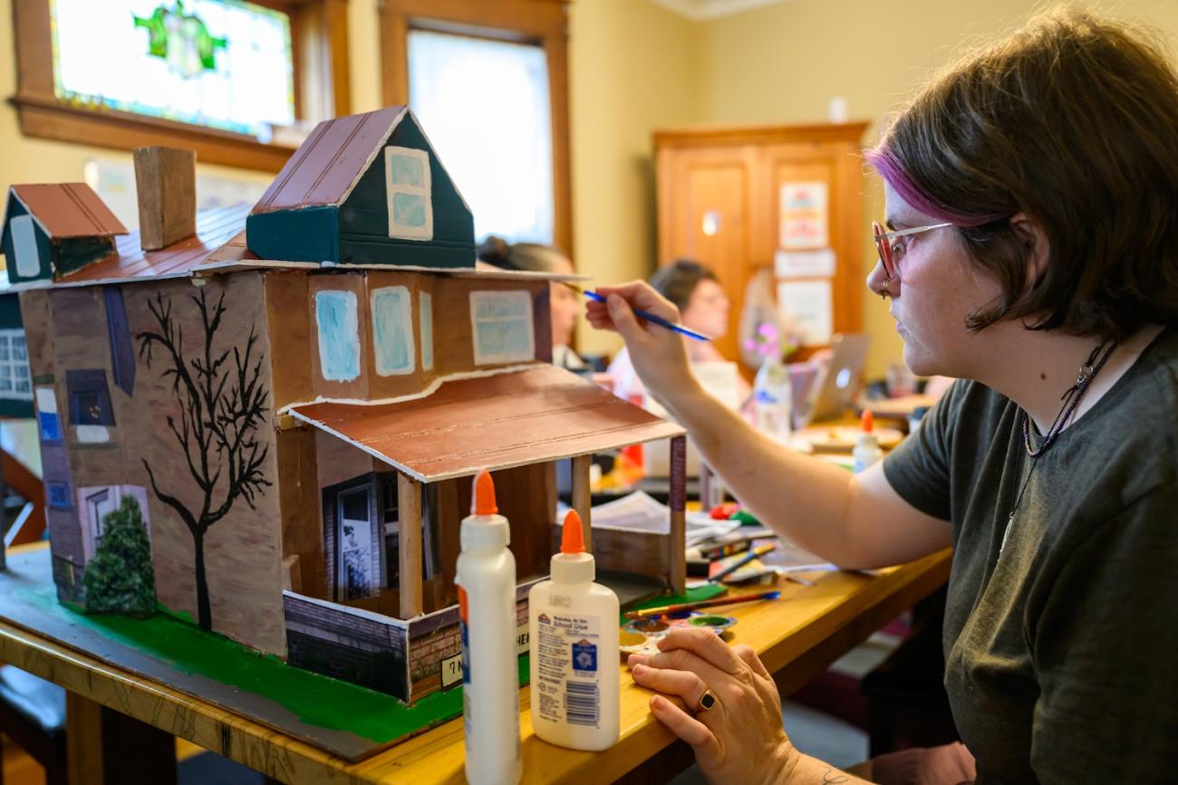 Reagan Klinger-Nevisa painting a model of a house