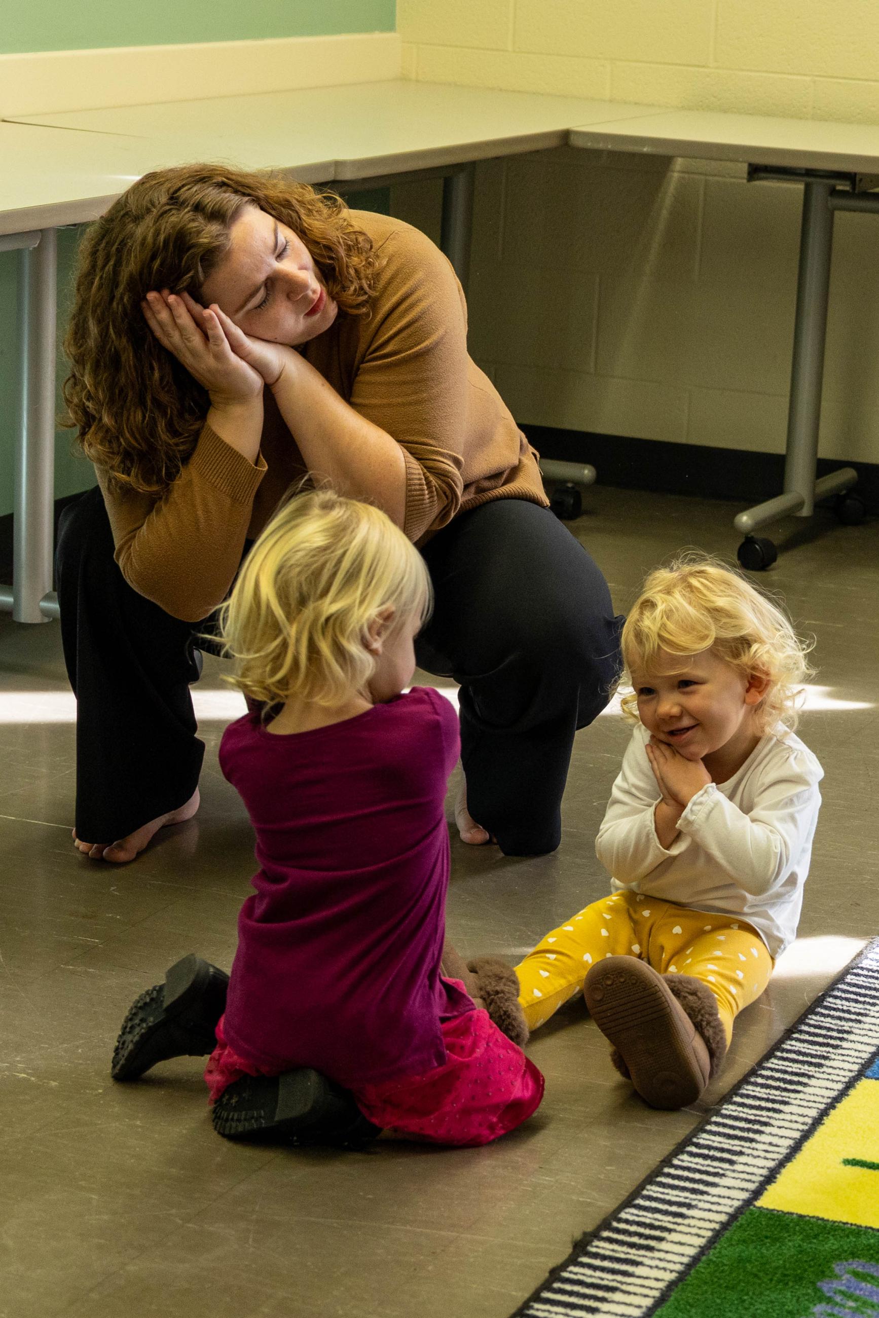 Teacher and toddlers make a "sleeping" gesture.