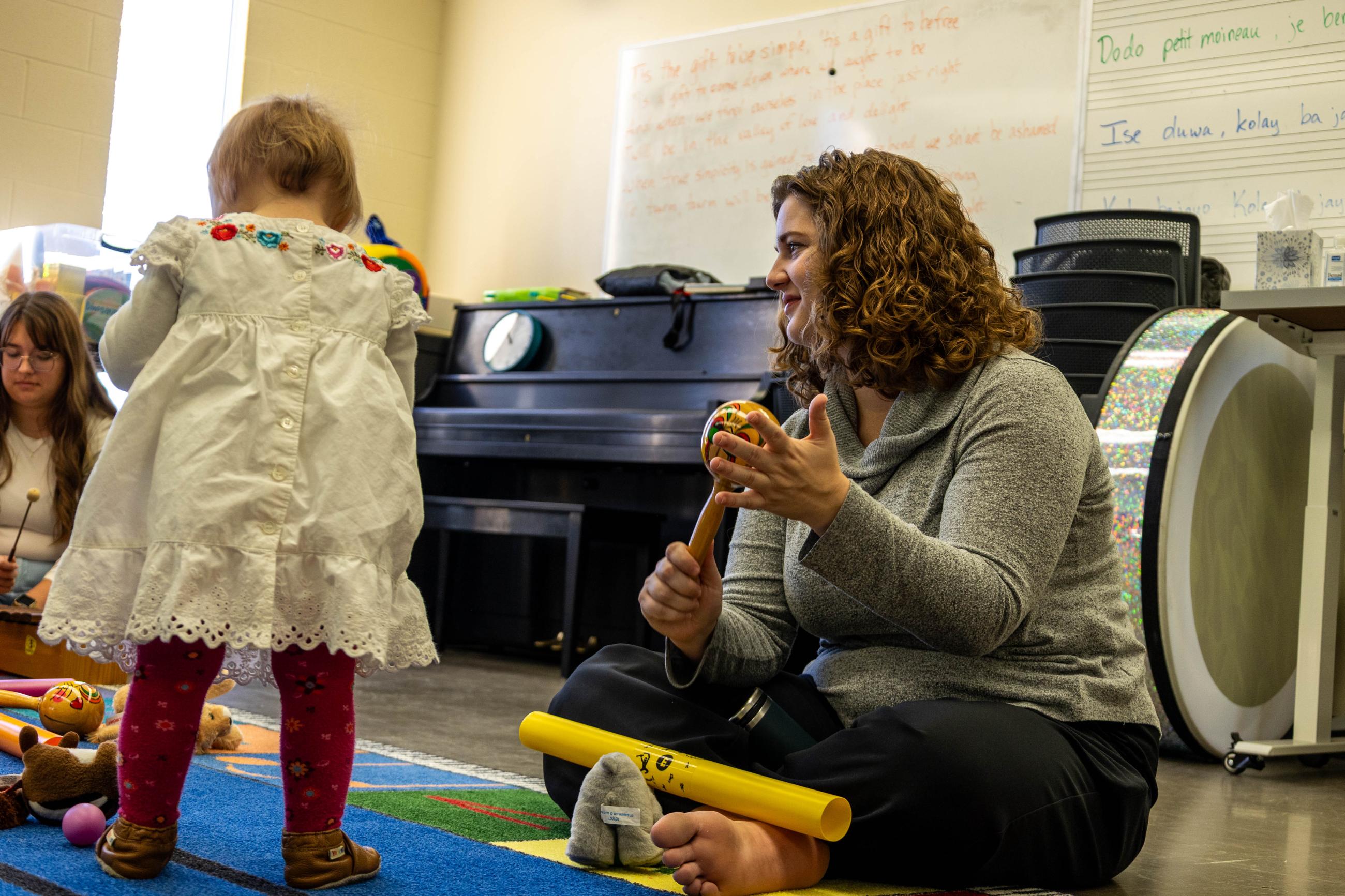 Teacher shakes a maraca for a toddler.