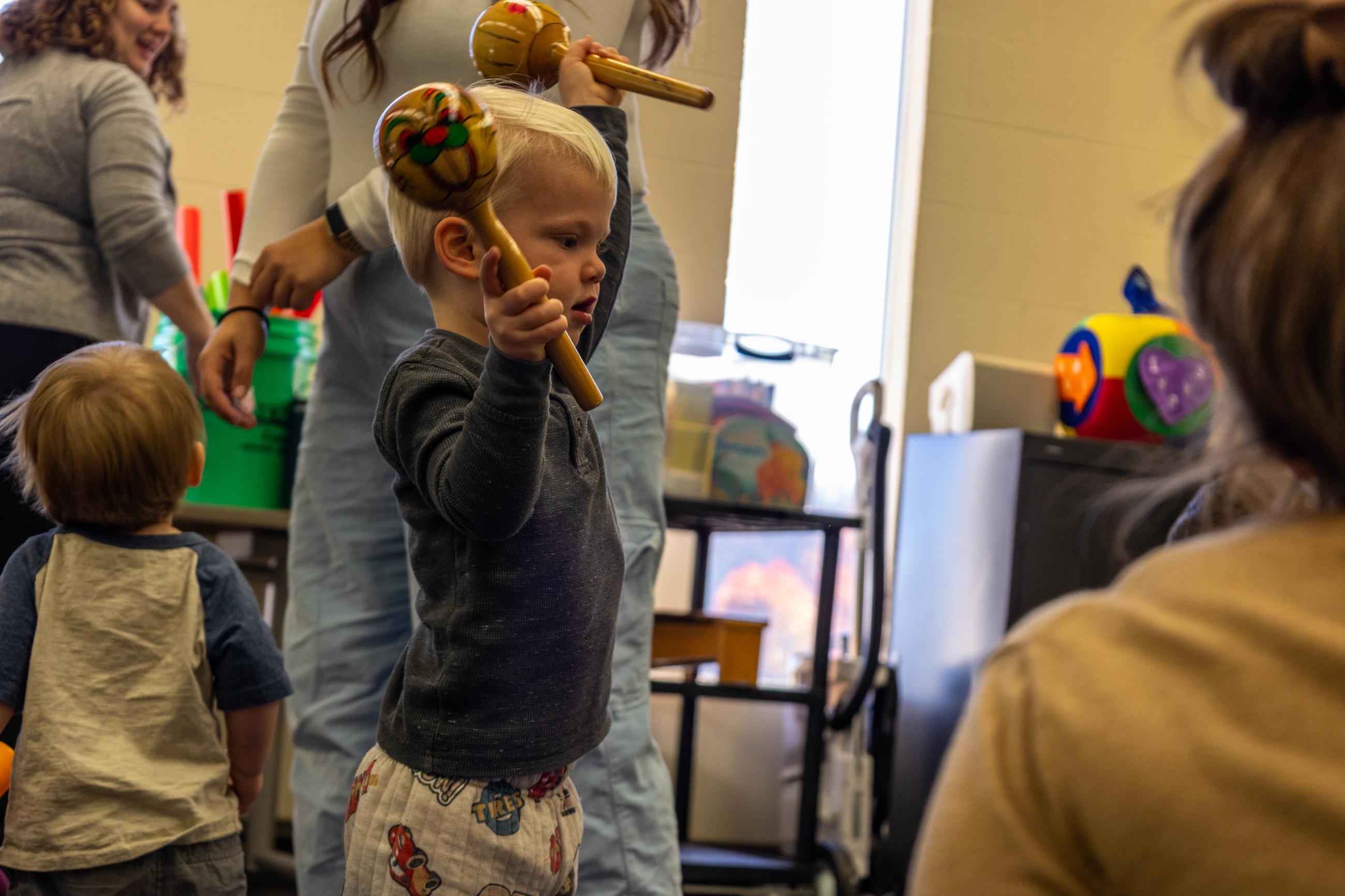 Toddler shakes wooden maracas.