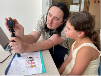 Calvin Nemeth in a children's hospital showing a camera to a child