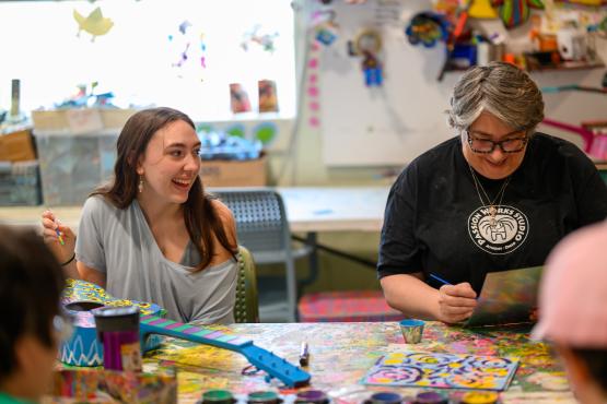 two women working on painting projects smiling