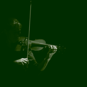Violinist plays against a dark green backdrop