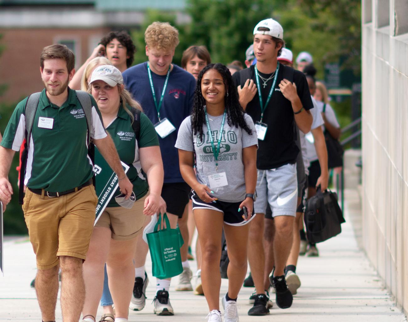 A group of students walking on the sidewalk toward the viewer