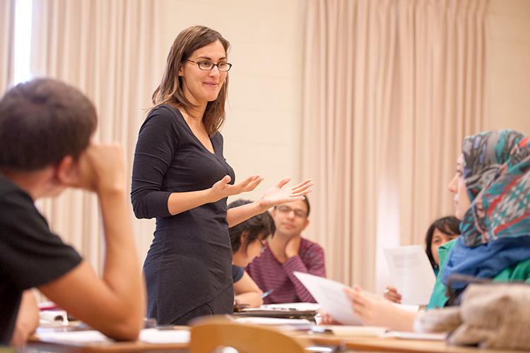 a professor standing in the middle of a room full of students teaching
