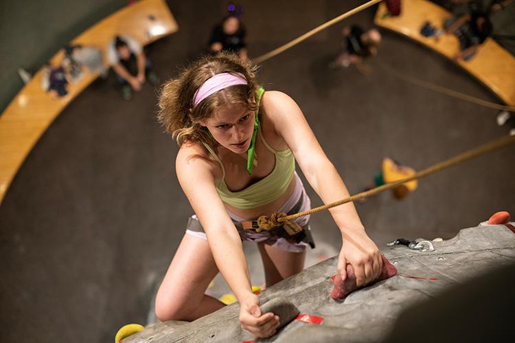 An aerial view of a female student climbing the climbing wall