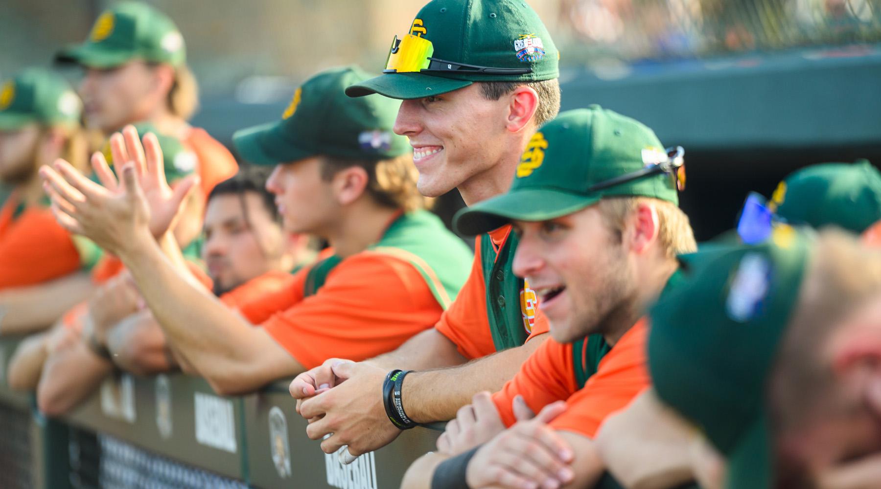 baseball players standing on the edge of the dugout