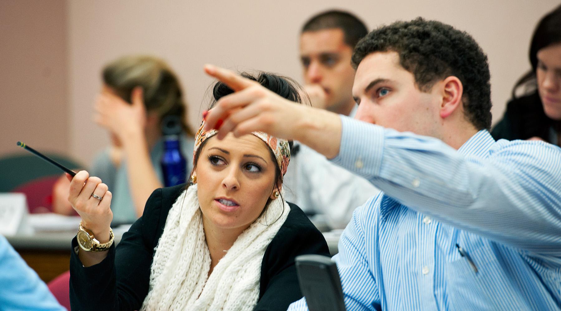 Two students are talking to each other while pointing to something in the distance