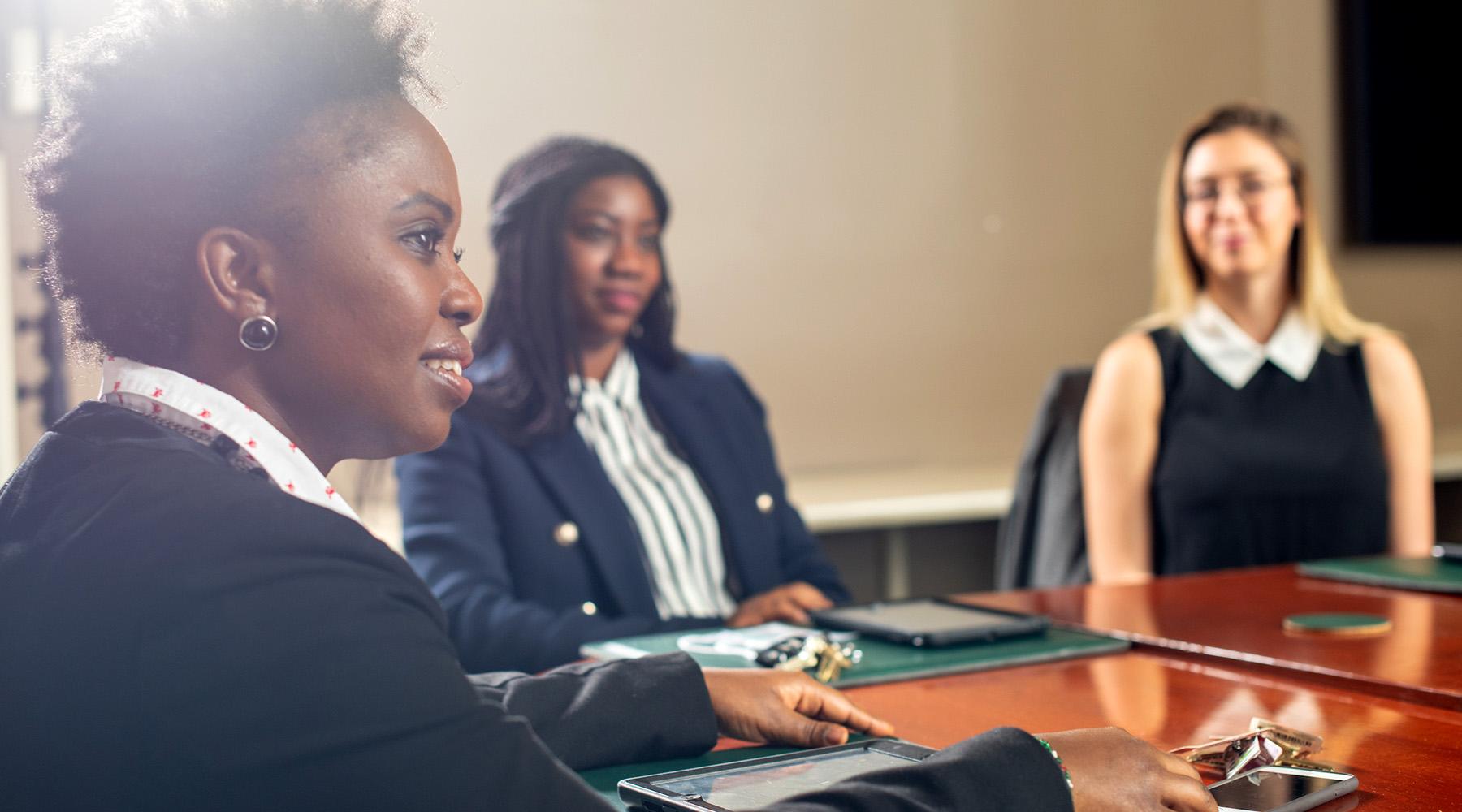 three women sit at a conference table