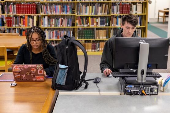 Two students study at computers in the library