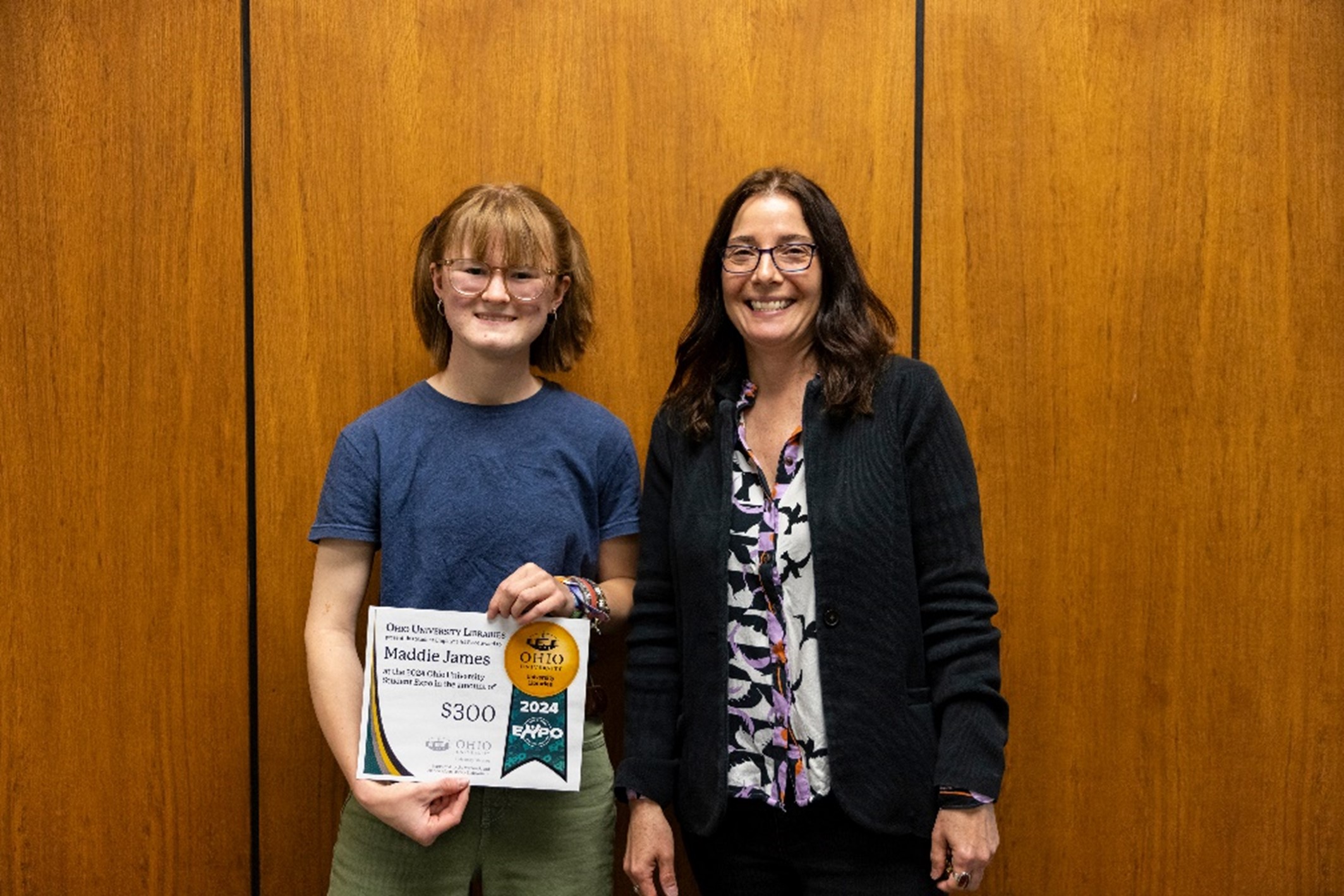 Photo of Madeline James posing with an award from the 2024 student expo alongside library dean Janet Hulm