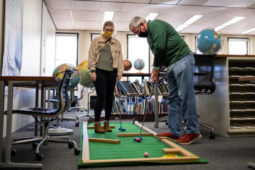 Father and daughter play a mini golf hole on the 5th floor of Alden Library