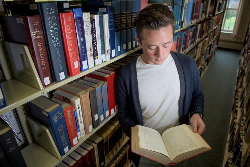 A student reads a book in the stacks of the Southern Campus Library