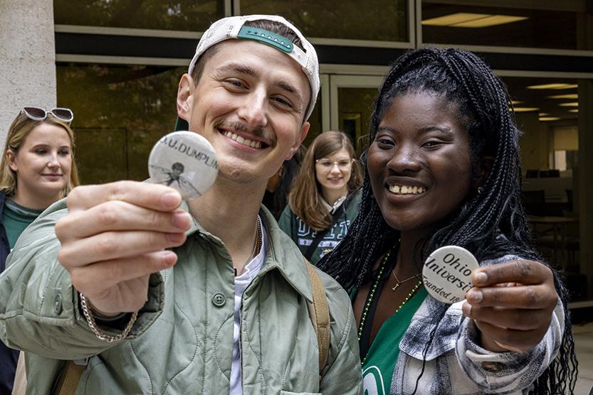 A young man and a young woman hold up buttons created from archival materials