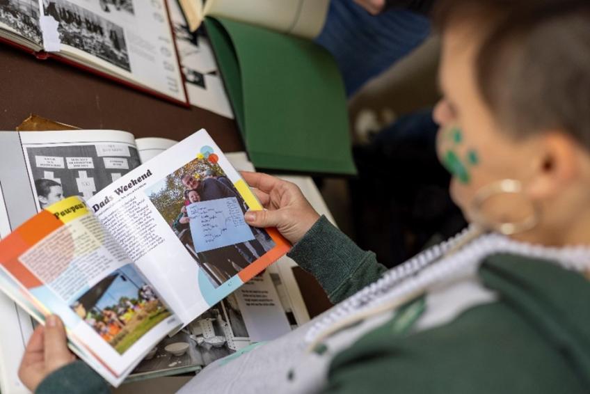 A person in Ohio University spirit apparel pages through a magazine