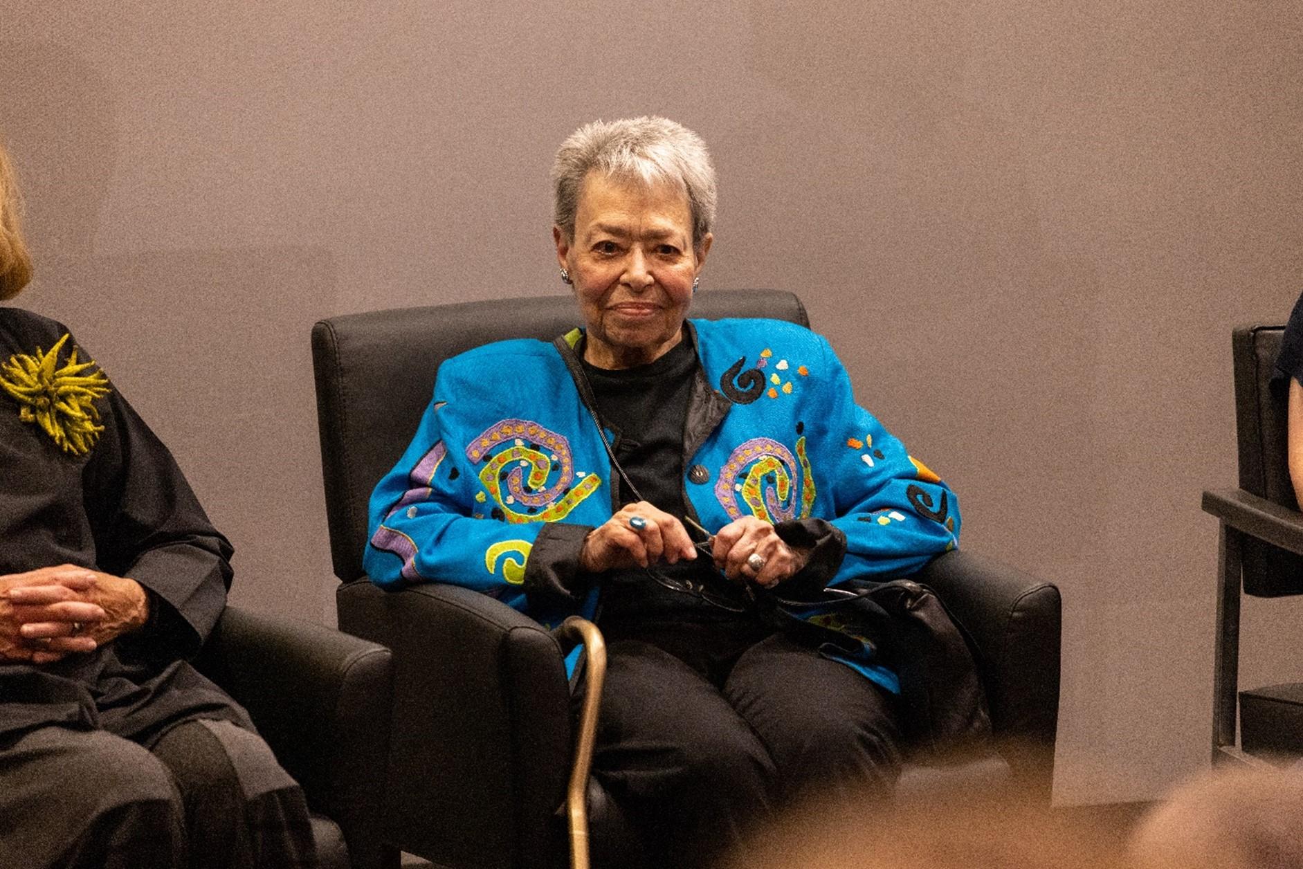 Picture of Gladys Bailin Stern sitting on stage smiling at the ceremony 