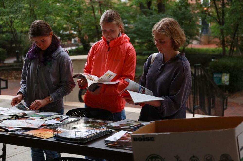 Students at Camp Alden 2025 flipping through magazines to cut images to make into buttons