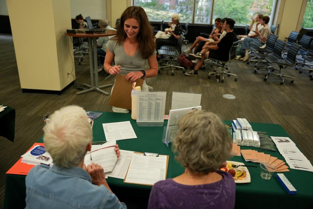From left, Mary Costello and Chris Knisley help Rose Nicola, a freshman studying journalism, register to vote on the fourth floor of Alden Library before the Venturing into Voting exhibit opening remarks. 