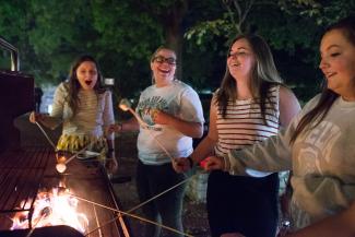 Students Roasting Marshmallows in front of Alden Library at Camp Alden event