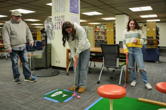 Freshman Sarah Shea lines up a shot on the 11th hole of Alden Open while her sister Hallie and father Thomas watch