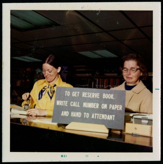 Two staff members work at the Alden Library reserves desk in 1971
