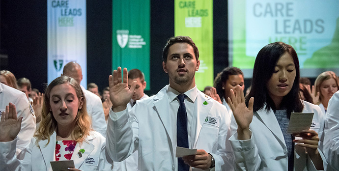 group of people in lab coats with their hand raised