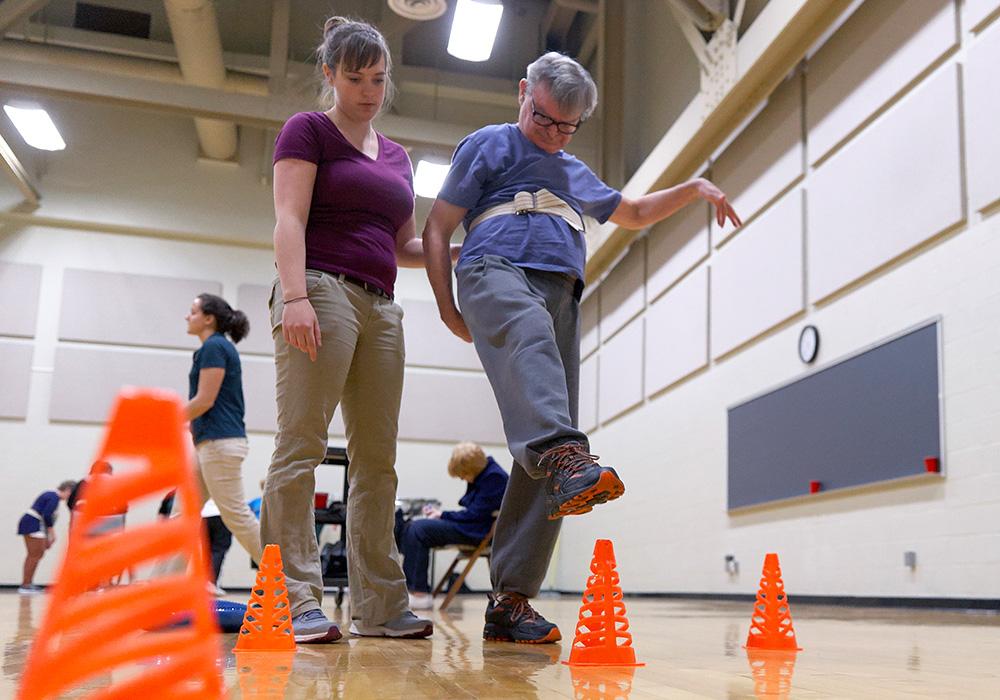 A woman helps a man with Parkinson's work on his balance