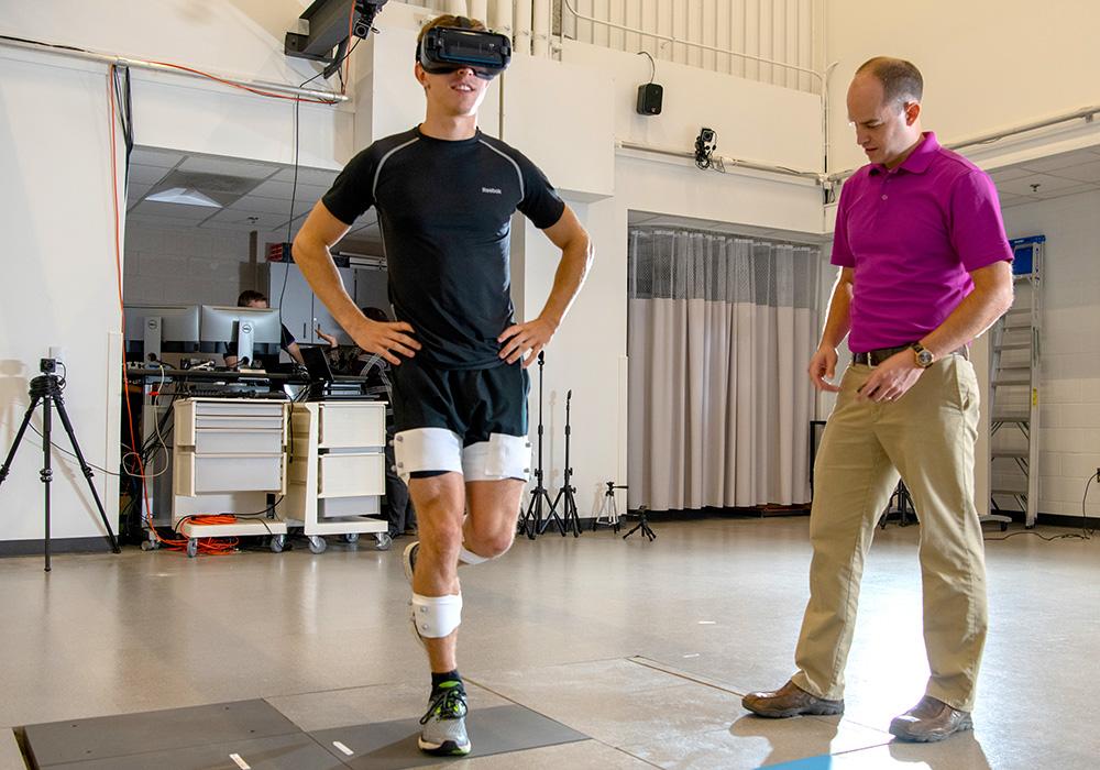 A man balances on one leg while wearing fitness monitoring equipment