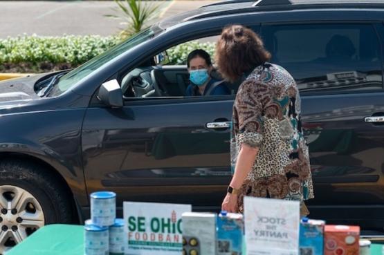 Woman collects food from a car during a drive-through event for Stock the Pantry.