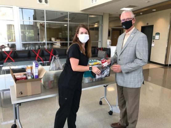 A student and professor pose in front of a table of food for the Dublin Food Pantry.