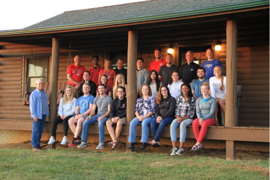 Students of the Rural Health Scholars post on a log cabin porch for a group photo
