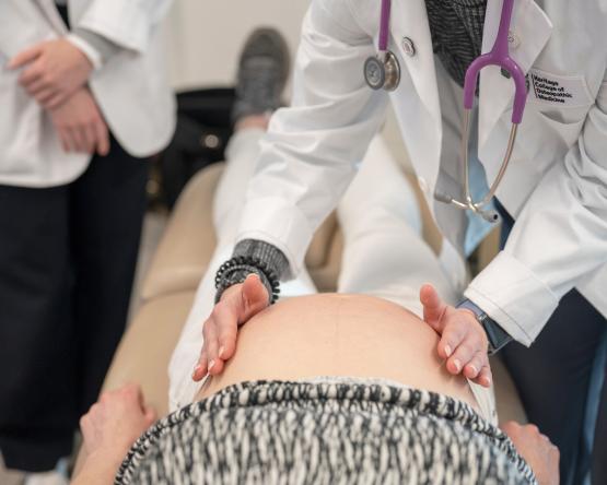 Medical students examine a pregnant woman during a lab