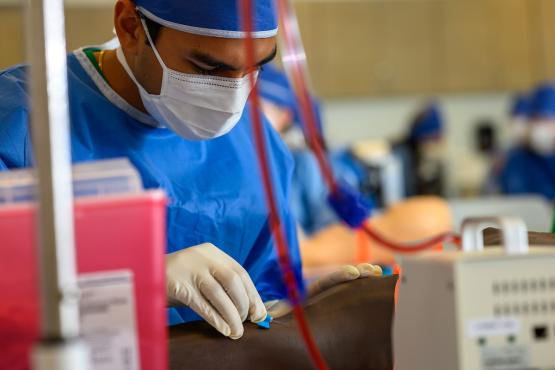 A medical student in scrubs sets equipment in a lab