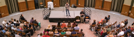 Man speaking into microphone in front of an audience