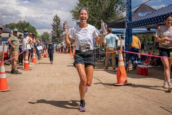  HCOM alumna Anne Flower runs through the aid station during the Leadville Trail 100 race.