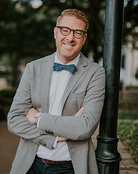 Man with blue bowtie and glasses smiling