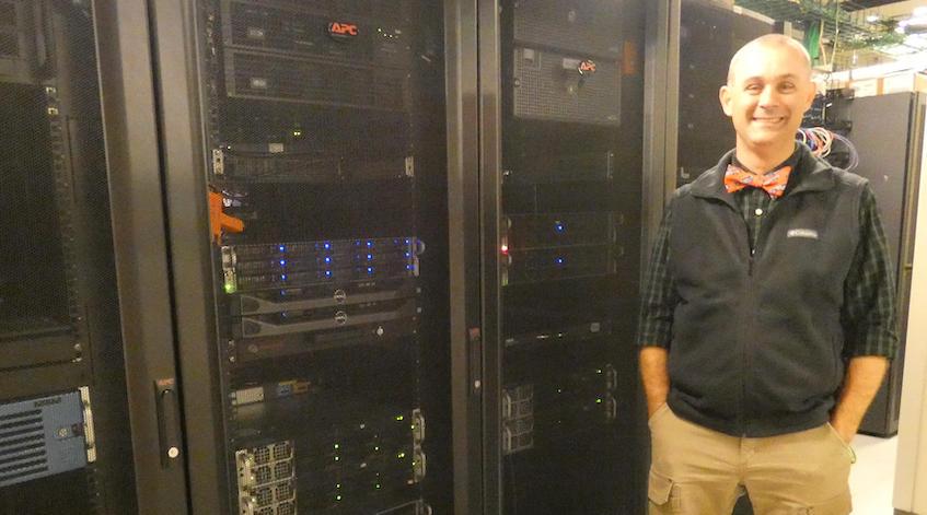 Bowie stands alongside networking equipment in the bottom floor of the Schoonover Center.