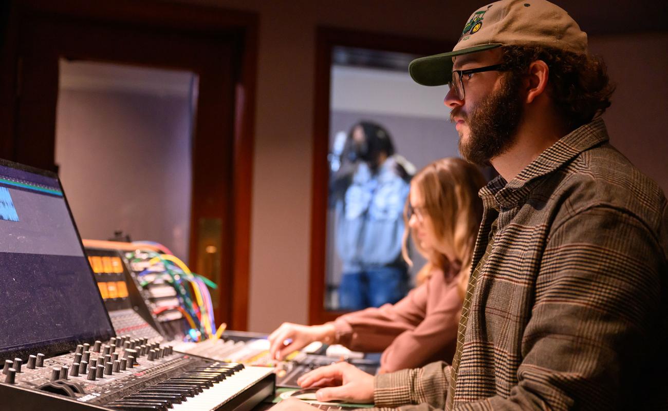 Student works with a sound board and other recording equipment