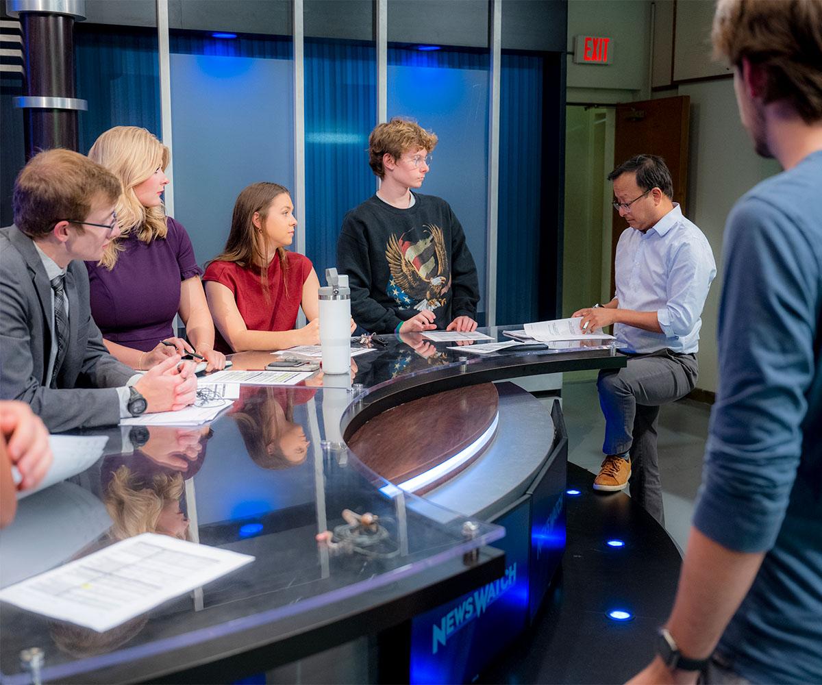 Students gather at a news desk on WOUB's News Watch.