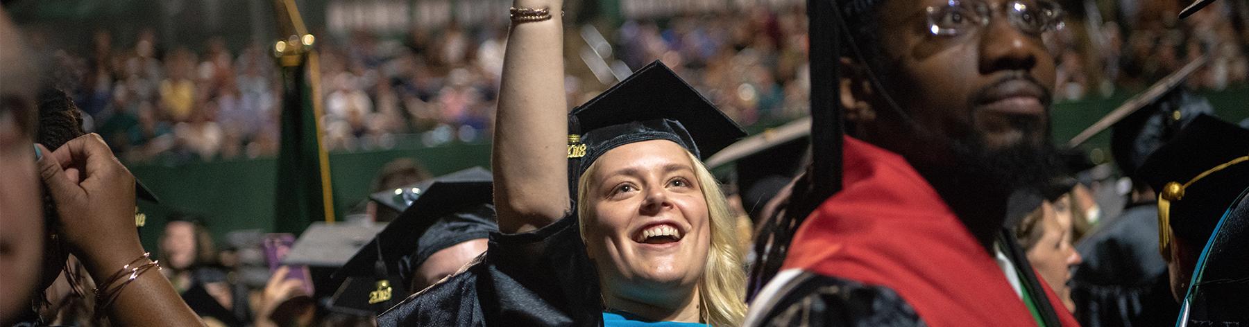 Graduate student waves at commencement